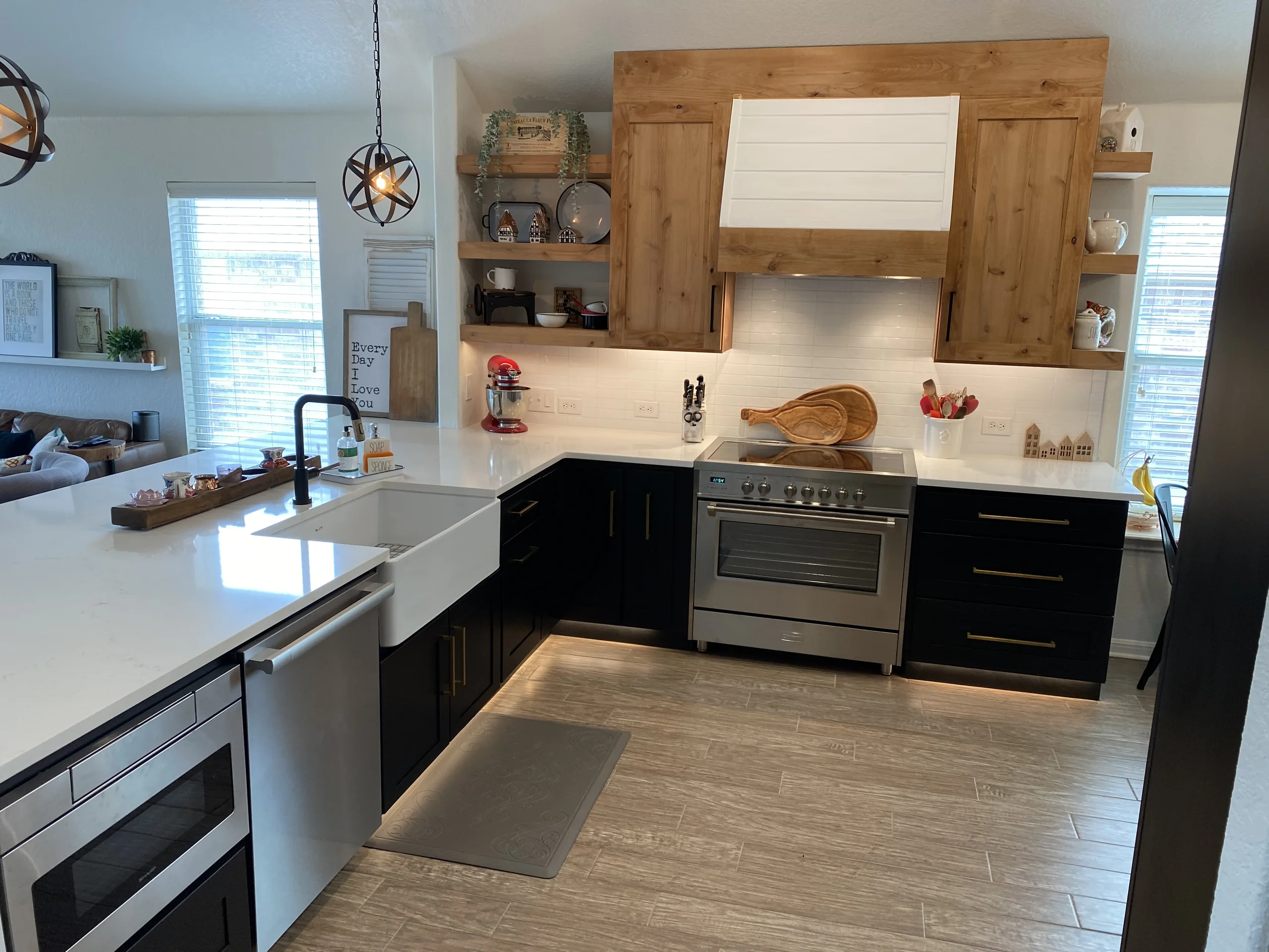 Charcoal kitchen cabinets under a stained wood range hood, built for a Fair Oaks Ranch home